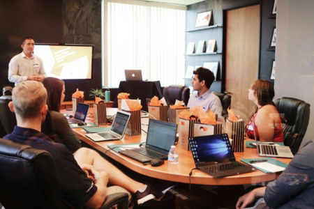 man-standing-in-front-of-people-sitting-beside-table-with-laptop-computers.jpg man standing in front of people sitting beside table with laptop computers